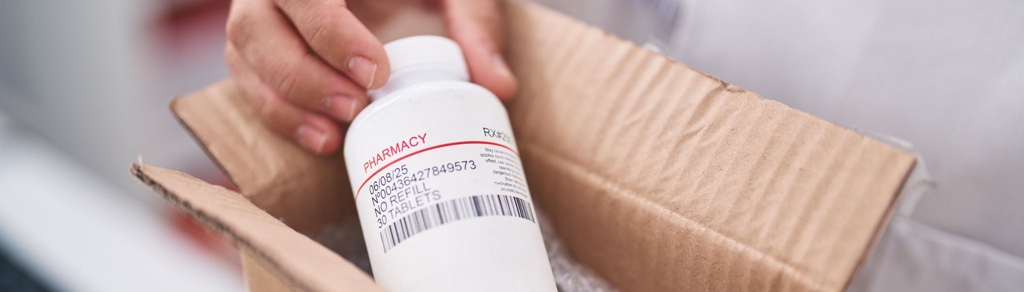 Young hispanic man pharmacist holding package with pills bottle at pharmacy