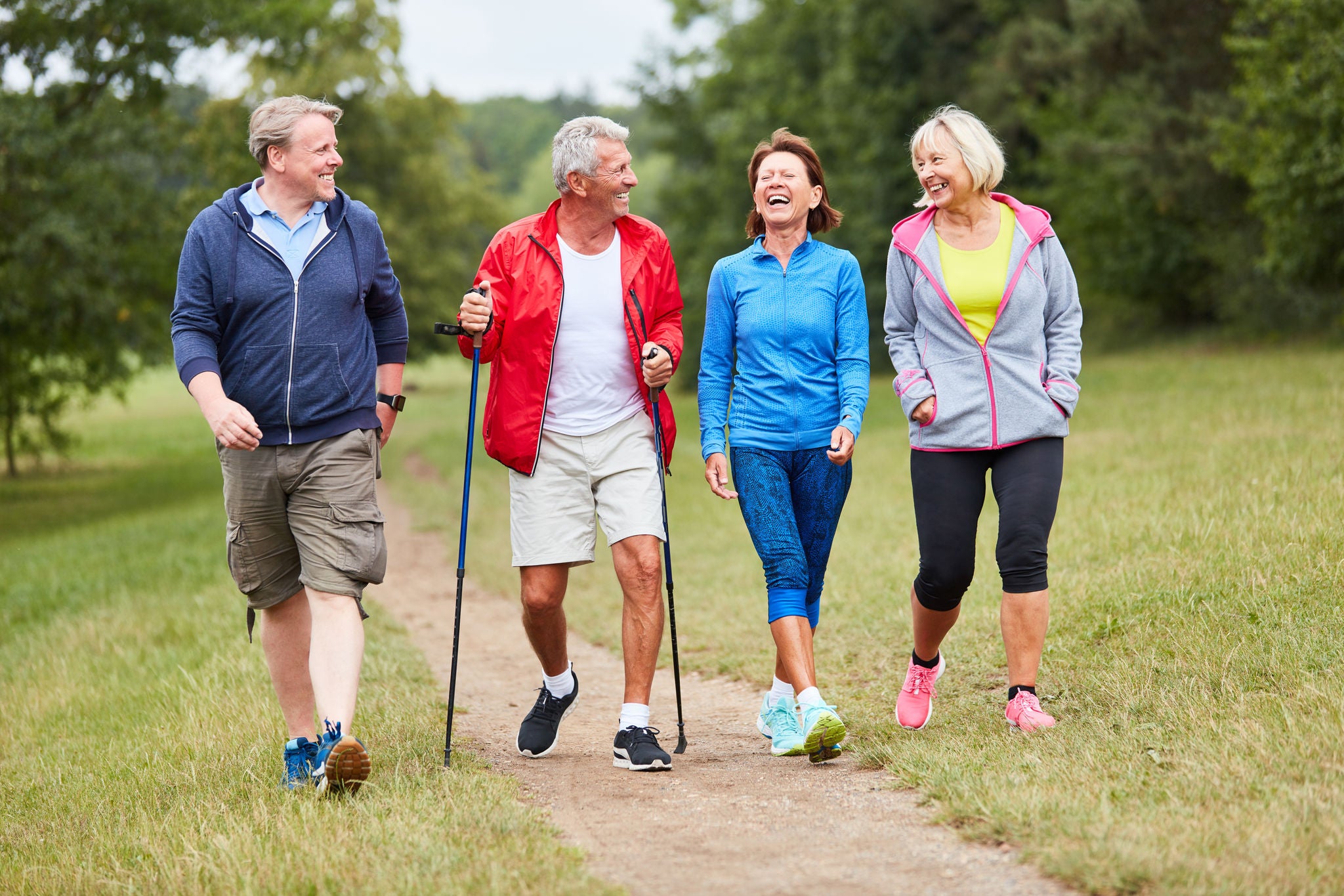 A group of seniors walks together outside on a trail