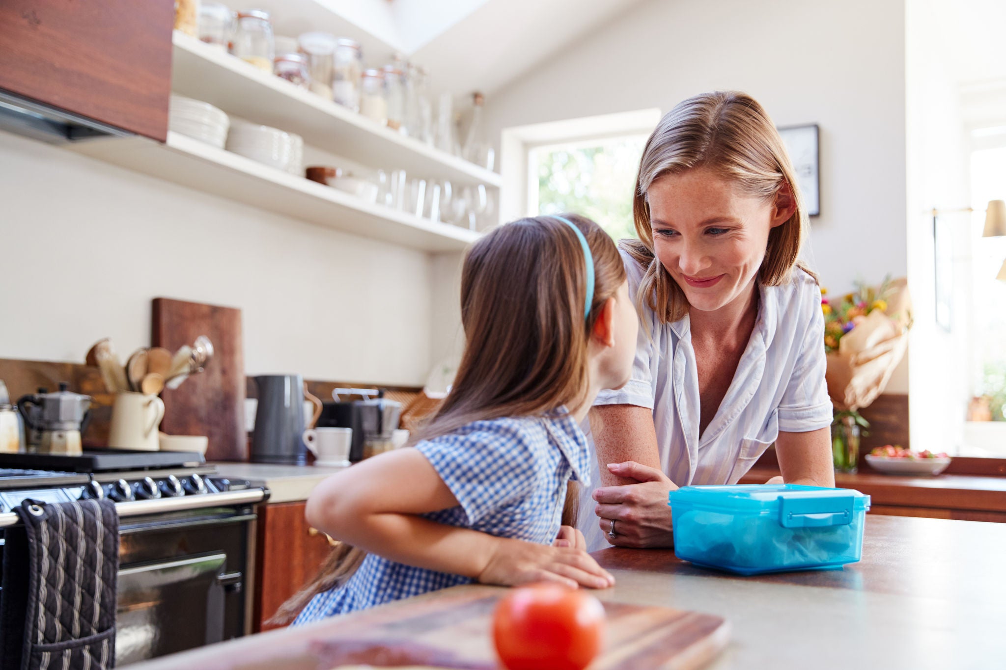 Same Sex Female Couple With Daughter Preparing School Lunchbox At Home Together