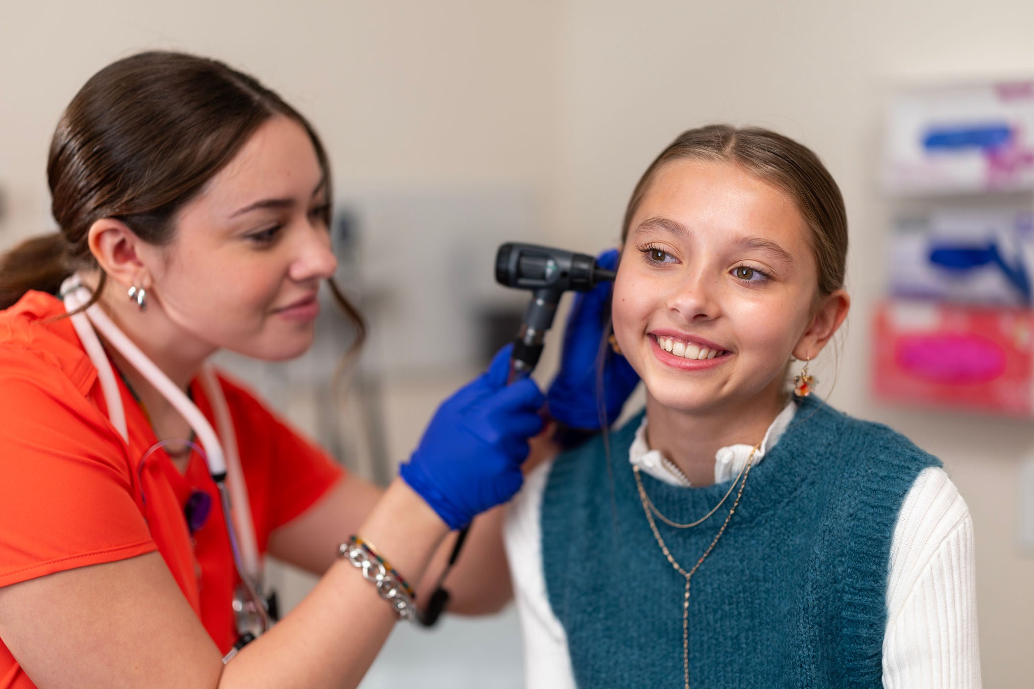 Nurse looks in a child's ear with scope
