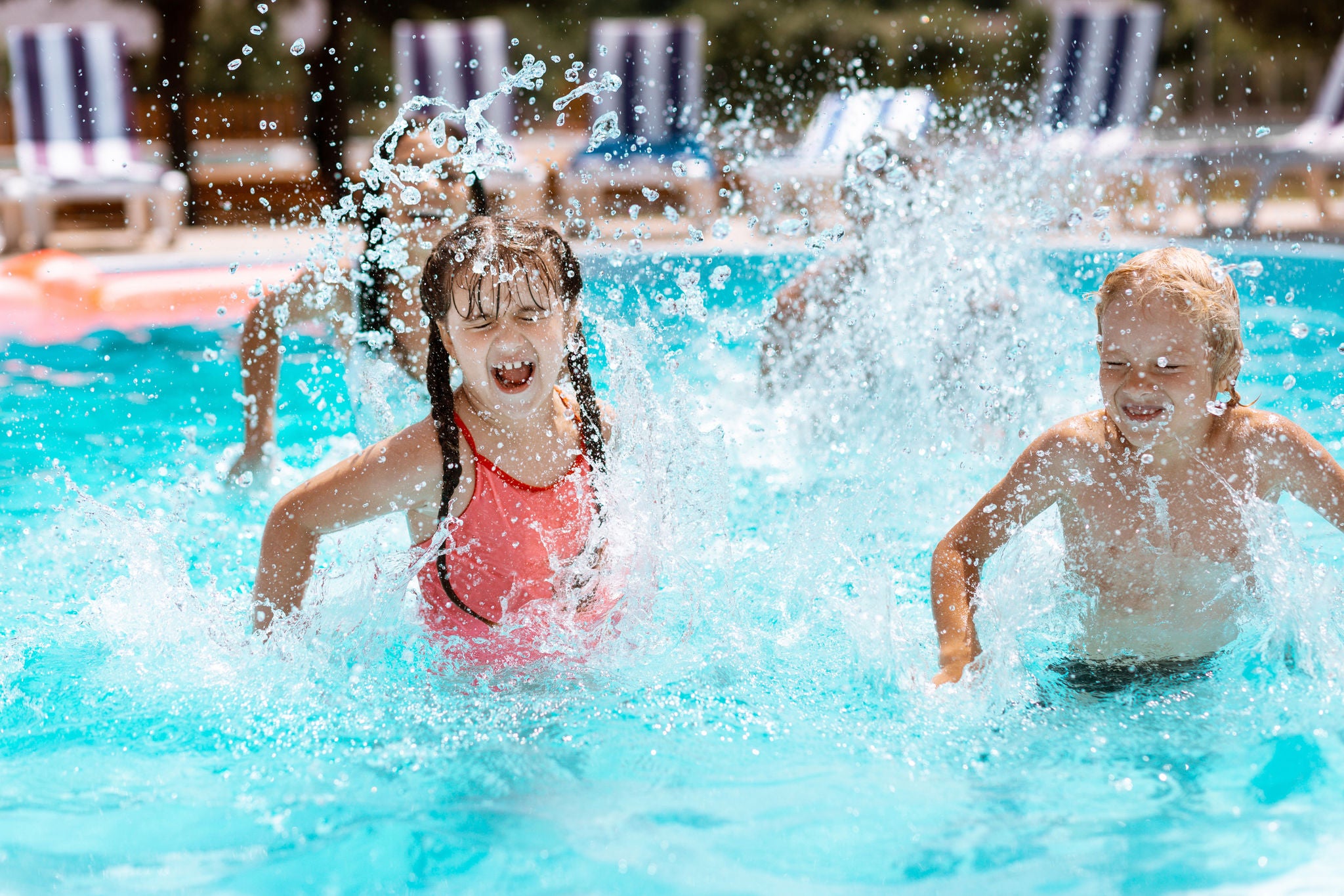 Children laughing. Cheerful happy children laughing while splashing water in swimming pool