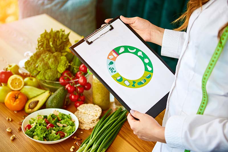 Dietista con tabla de alimentos saludables para mostrar a la paciente.