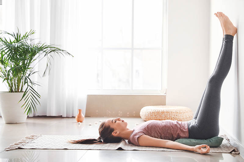 Woman practicing yoga at home to relieve stress and anxiety.
