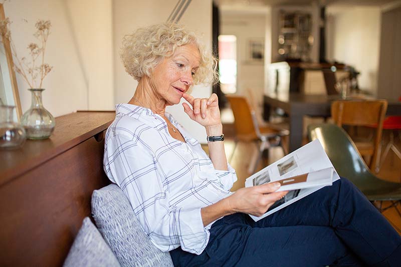 Senior woman reading an Alzheimer's Disease magazine at home.