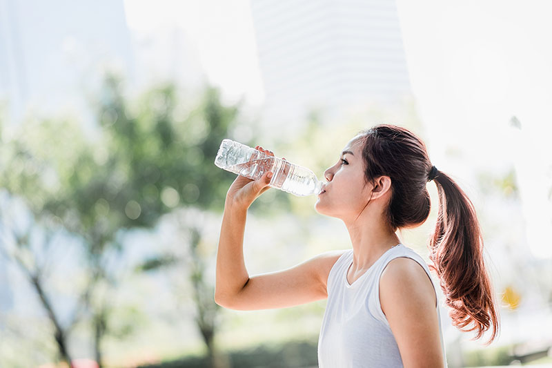 Woman drinking water to stay hydrated while exercising outside.
