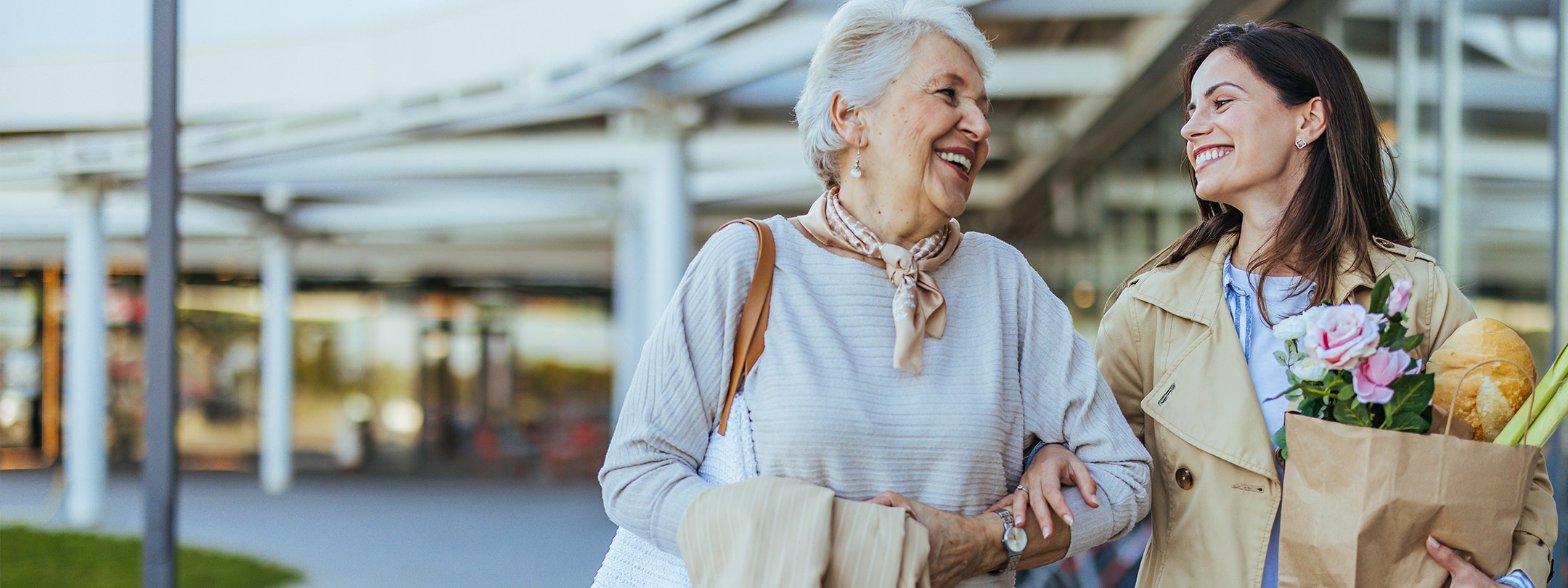 An older woman and younger woman walk with groceries.