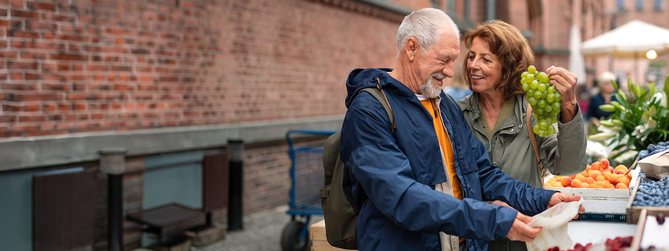 Happy older couple holding grapes at street market