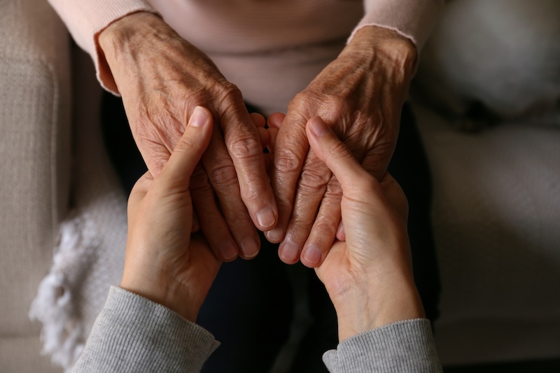 young hands gently holding elderly hands