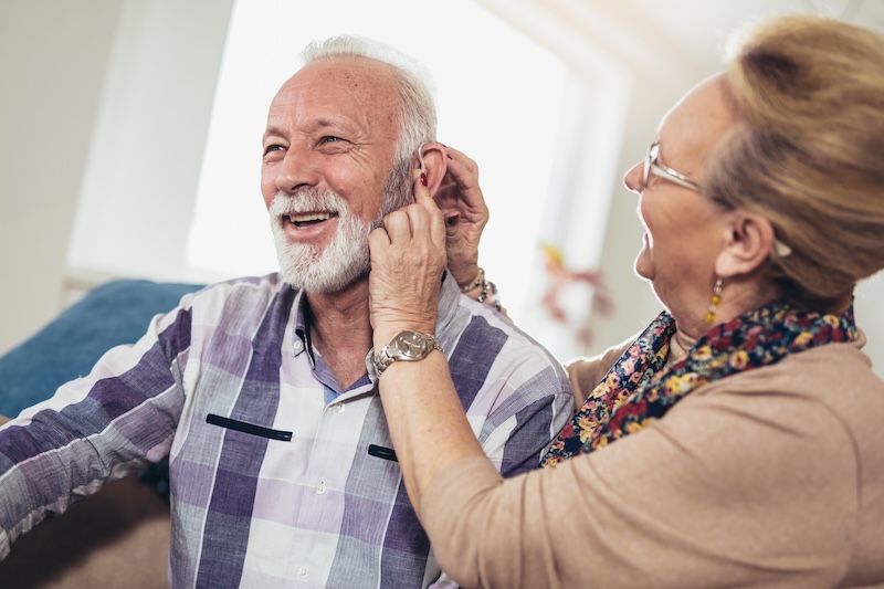 A woman checking a man's hearing aid