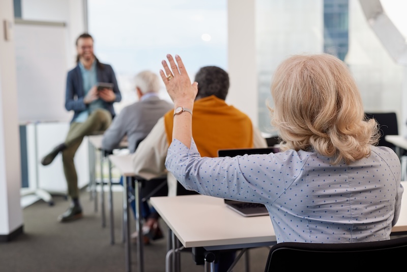 Woman raising her hand in a classroom with an instruction