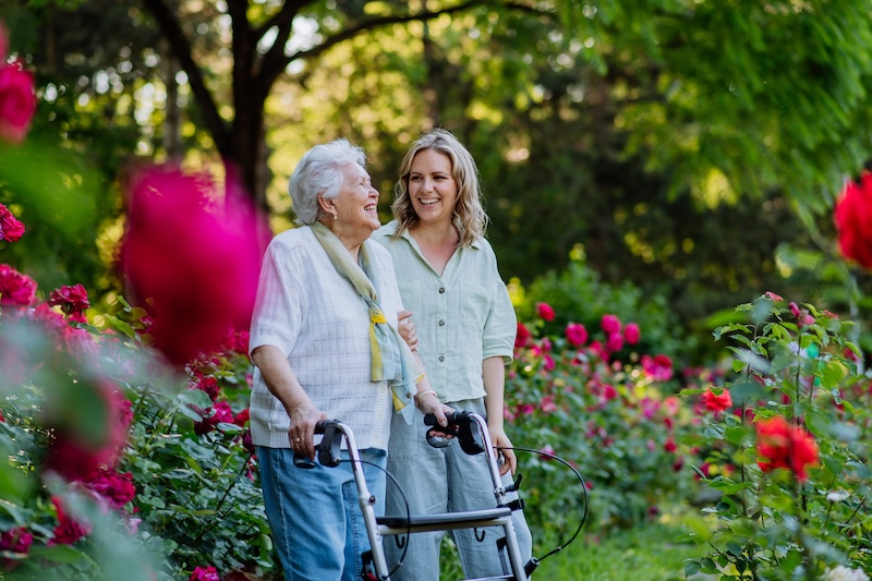 Senior woman walking with caregiver in garden