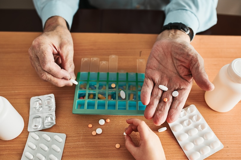 hands holding medicine with a weekly pill container