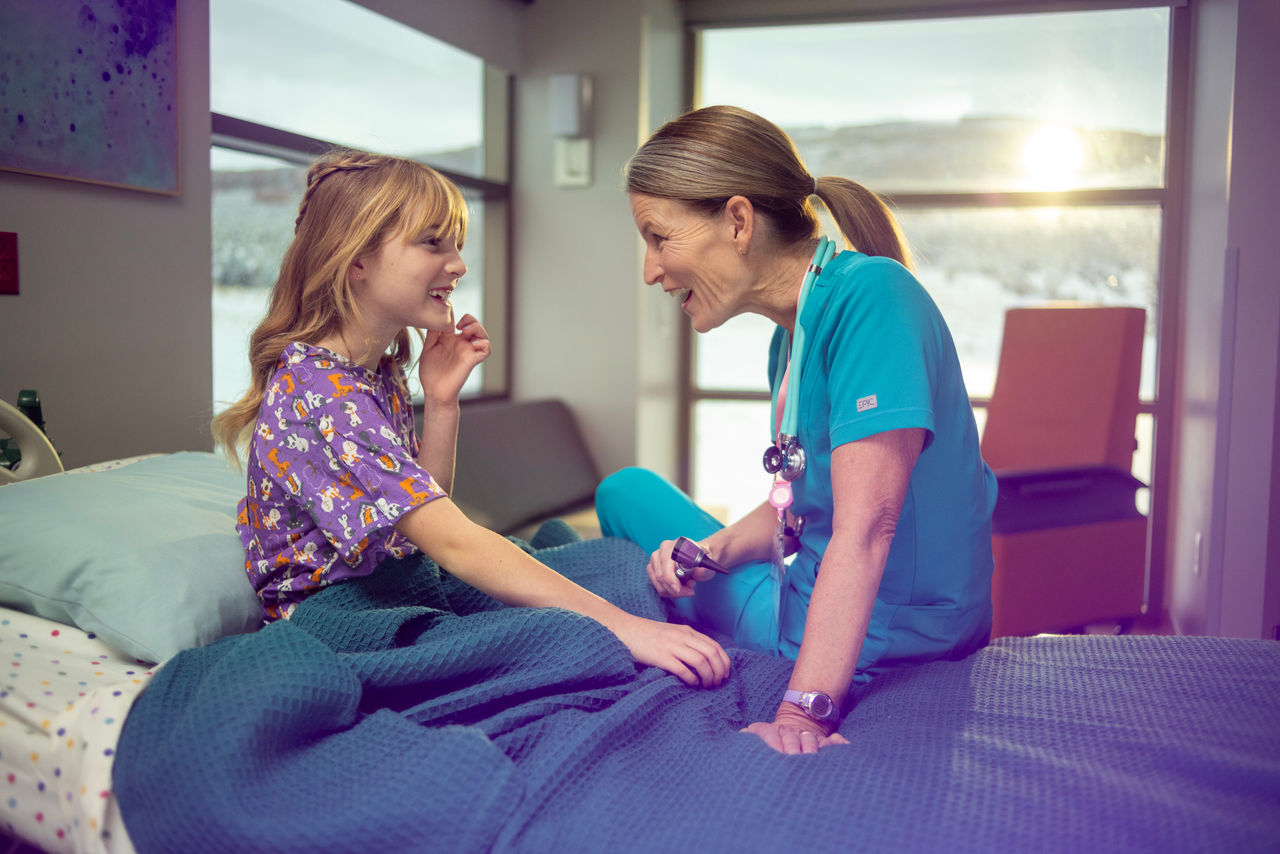 Nurse comforting young girl in hospital room