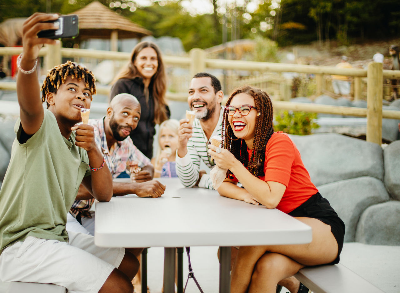 Teenage boy taking selfie with friends and family while having ice cream at golf course