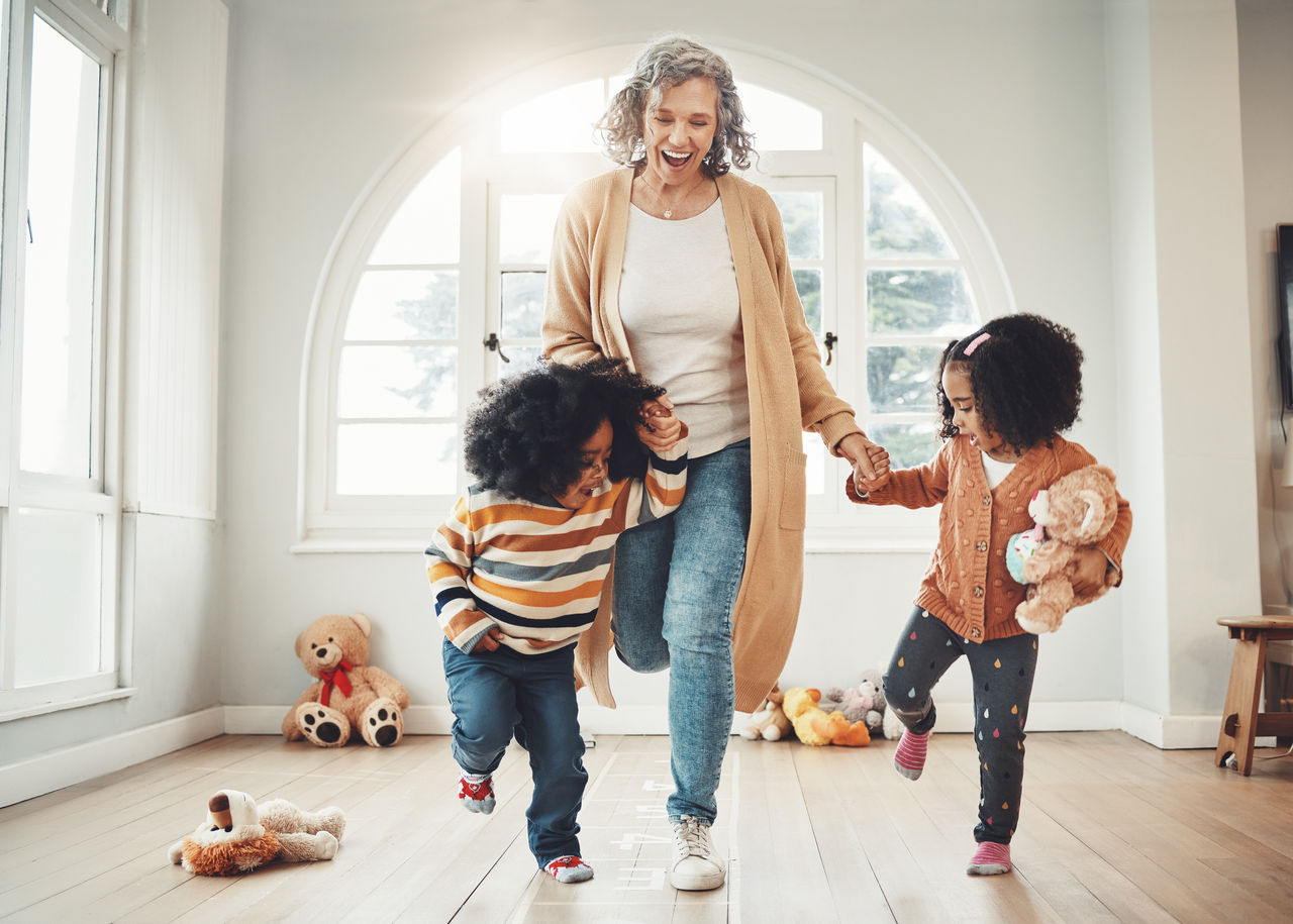 Hopscotch, grandmother and children play in home having fun, enjoy games and balance together in bedroom. Happy family, entertainment and grandma with kids for jumping, playing and numbers activity.