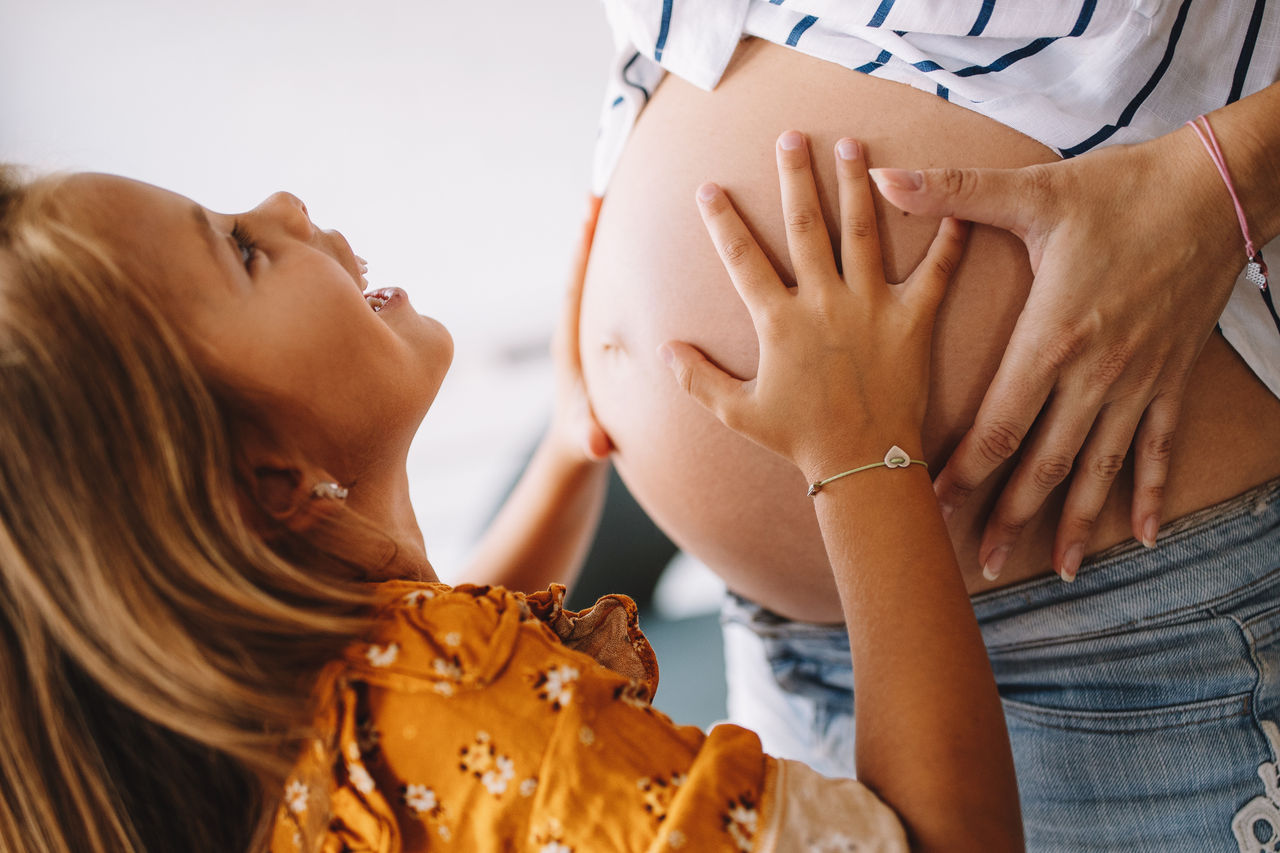 Beautiful pregnant woman with cute child, daughter. Pregnancy, family, love concept.