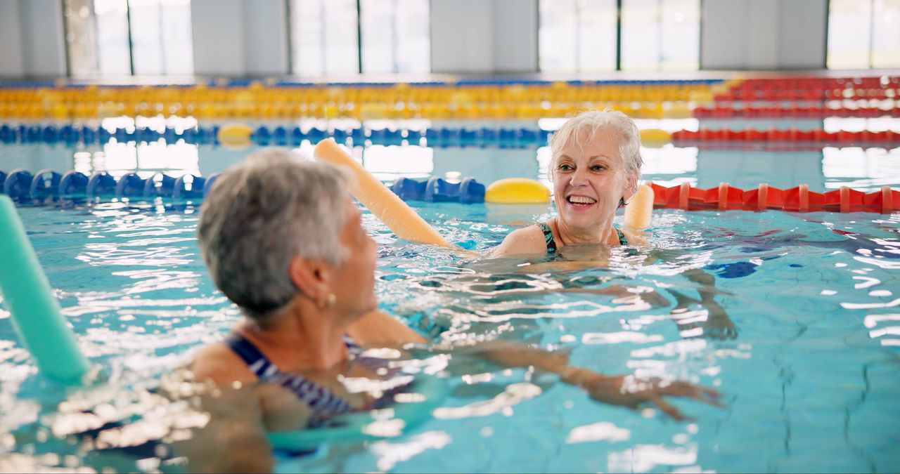 Smile, training and mature women in swimming pool for exercise, healthy body and strong muscle. Friends, water and aerobics class for fitness, physiotherapy or rehabilitation of happy senior people.