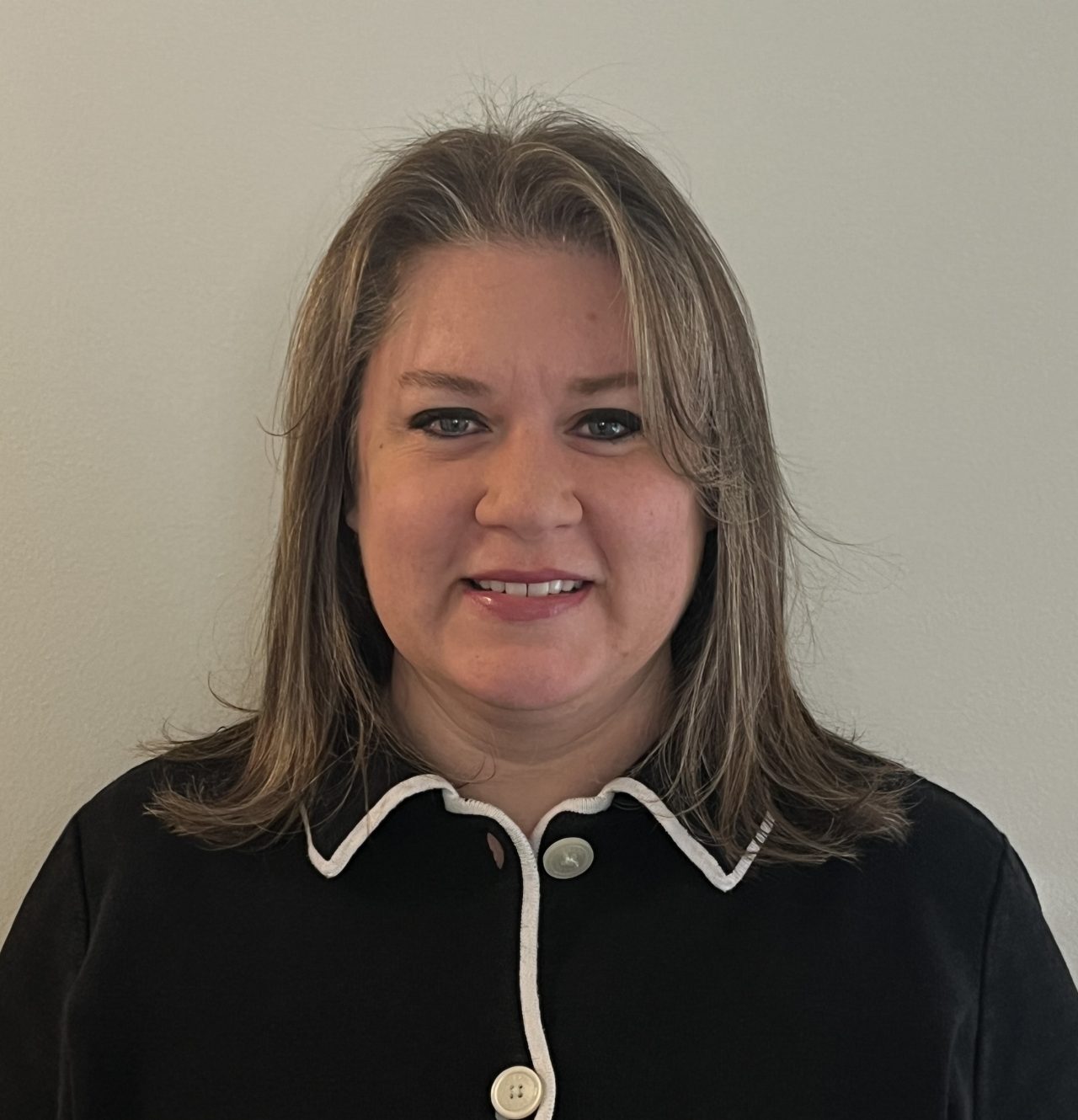 Image of a smiling woman in a black shirt in front of a gray background