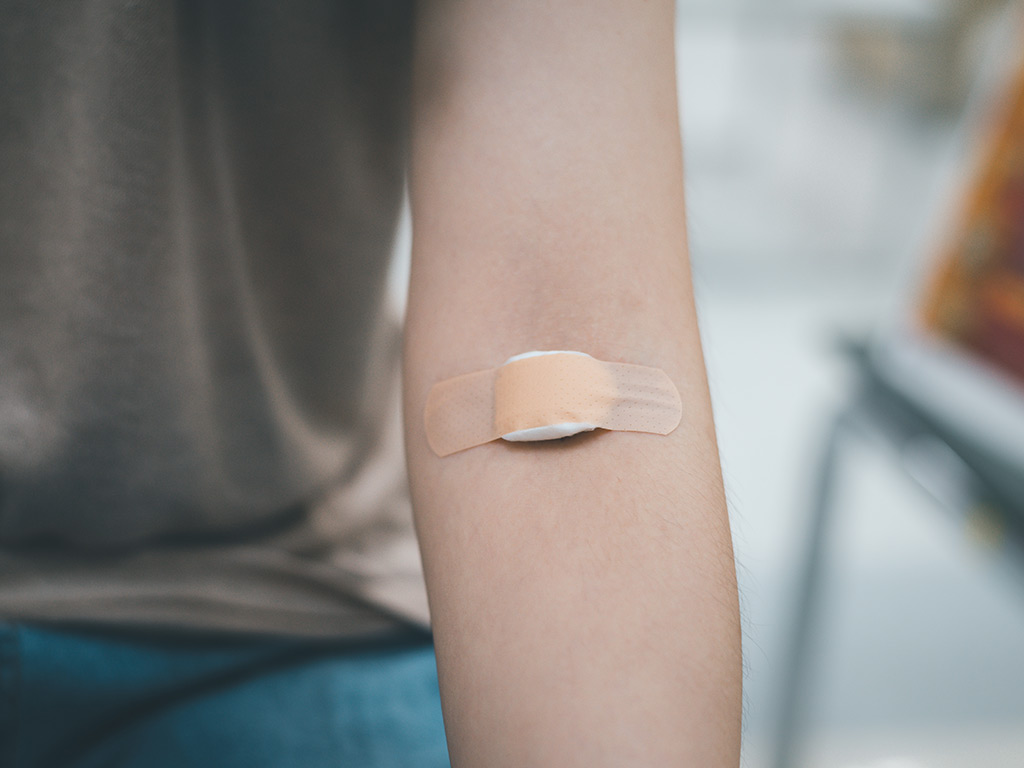 La mujer tiene un vendaje sobre la cara interna del codo después de realizarse un análisis de sangre.